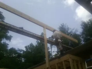 Carpenter setting a ridge beam over a new addition frame — Ice Dam Removal by Roofing Brothers in Coal Center