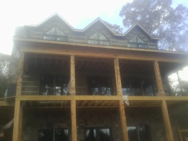 Dormers and porch framing on a large log home under construction — Roof Coating work by our crew in Coal Center