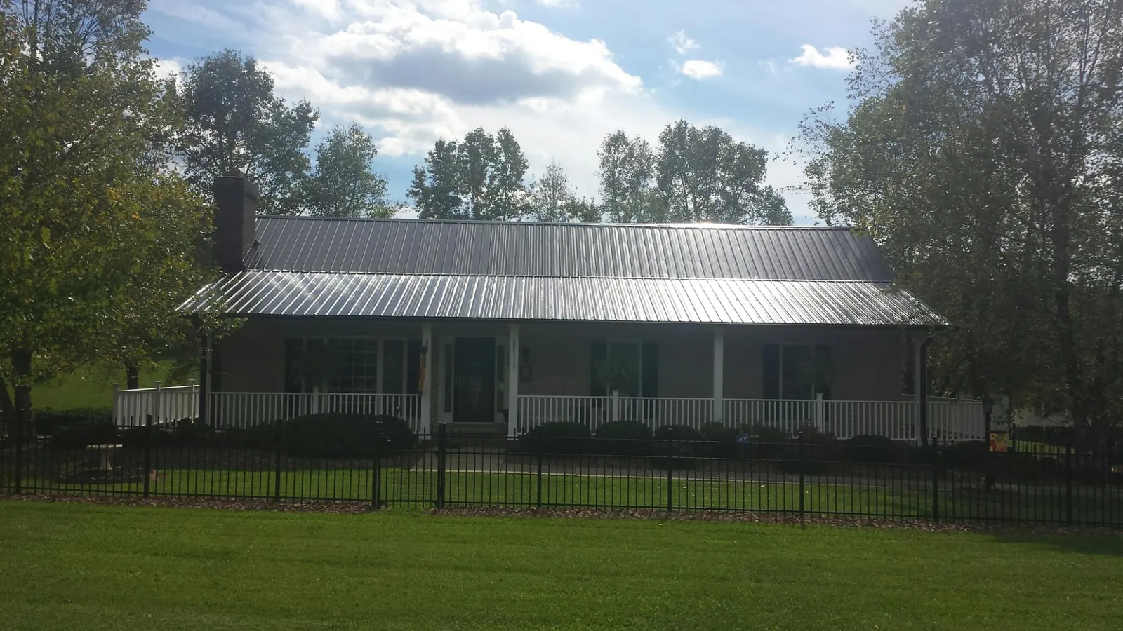 Gray metal roof on a brick ranch with a full width front porch — Gutter Guard Installation work by our crew in Coal Center