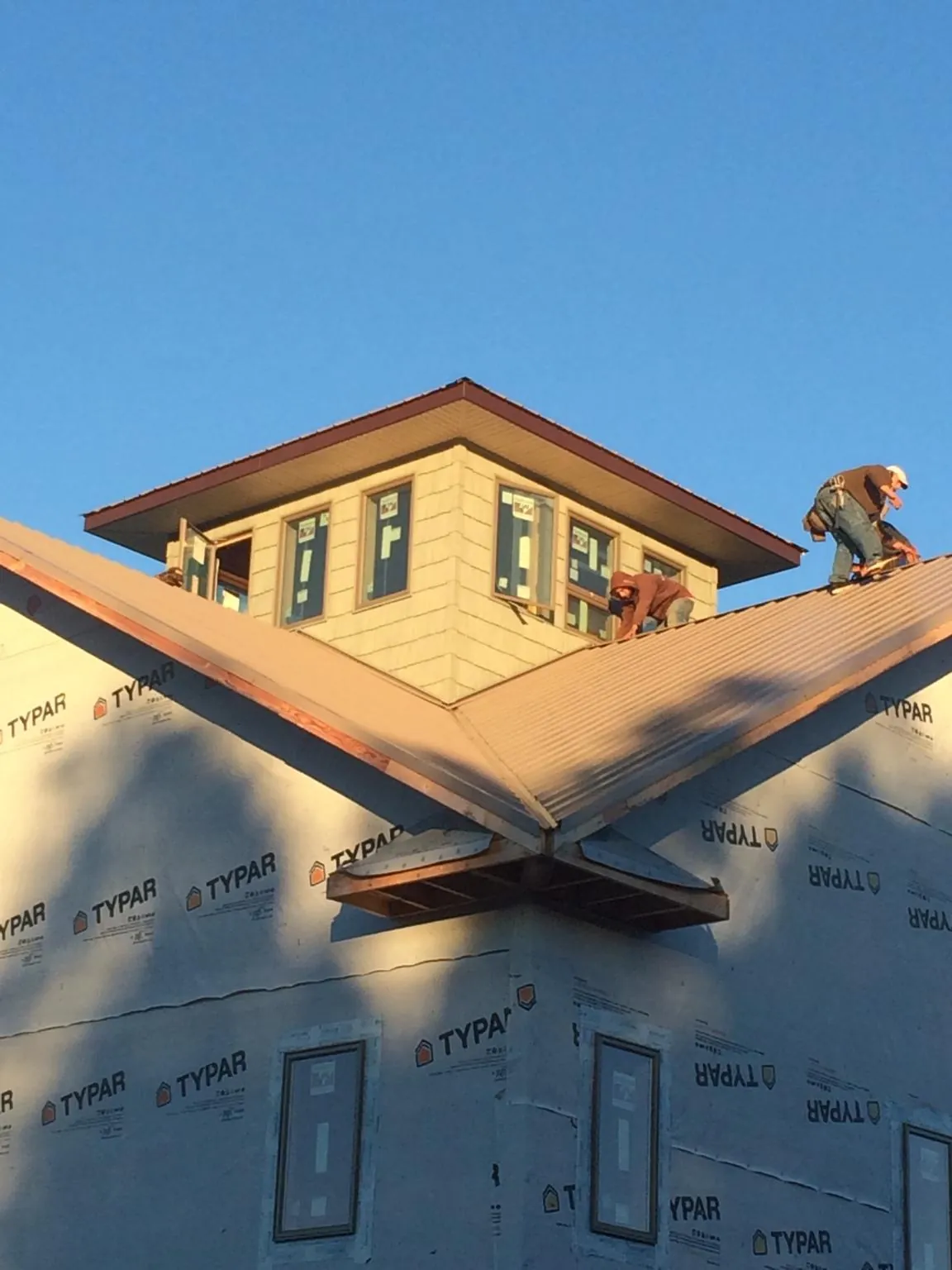 Roofers working around a rooftop cupola on a new metal roof at sunset — Roof Waterproofing in Coal Center by Roofing Brothers